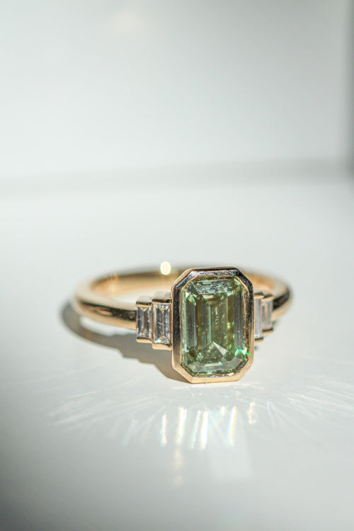 emerald cut green diamond in an art deco setting with white diamond baguette side stones