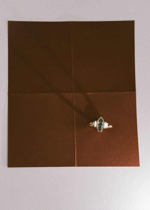 A yellow gold ring with a green diamond marquise center stone and white diamond side stones. (view 3)