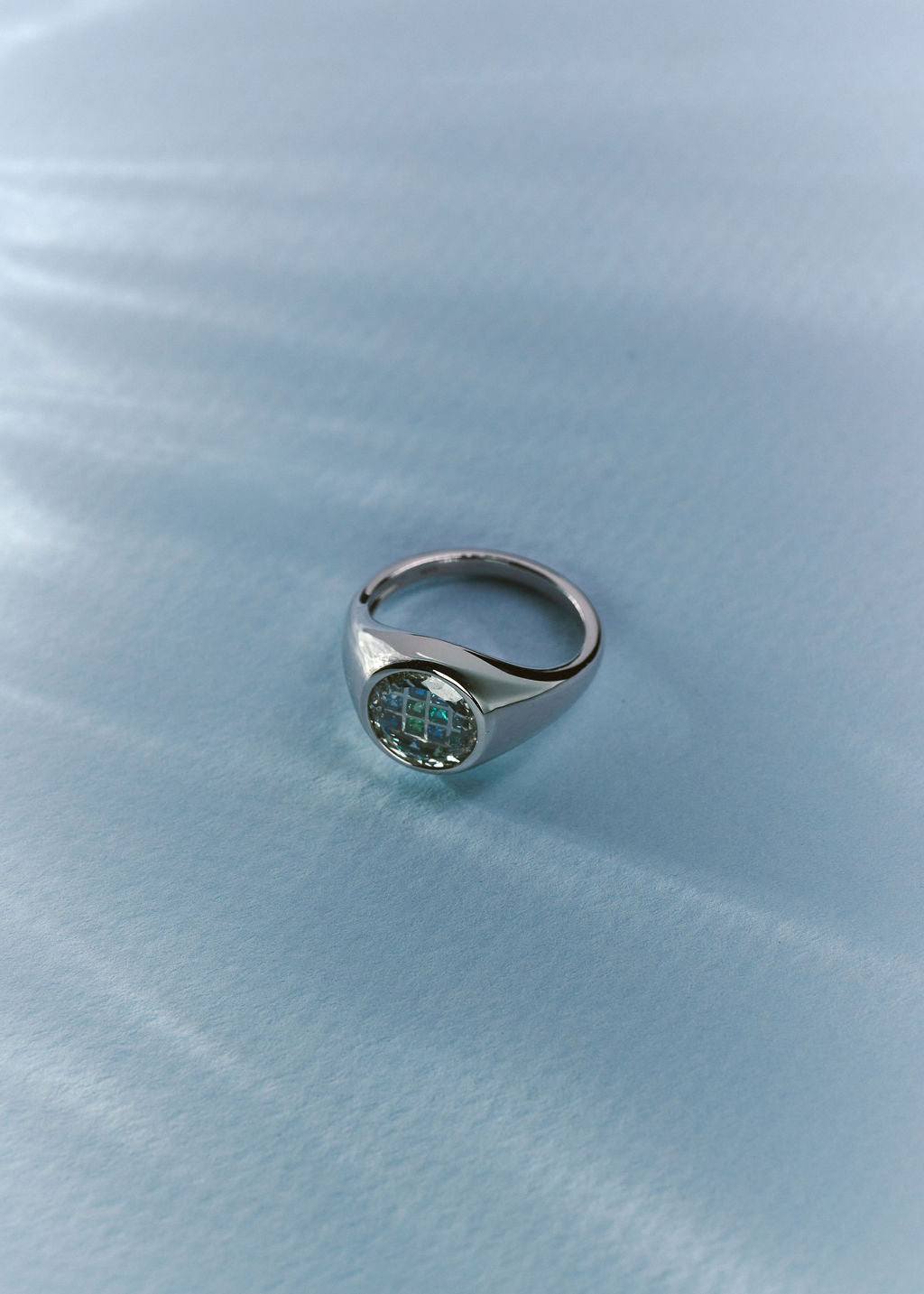 A silver signet ring with a round face and gemstones in blue-green shades. (view 6)